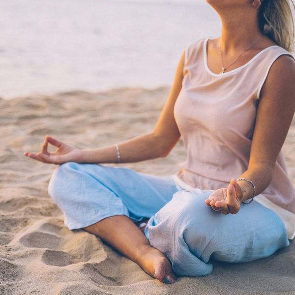 Person meditating peacefully outdoors during sunset.